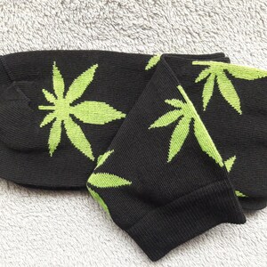 May include: A pair of black socks with a green marijuana leaf pattern.