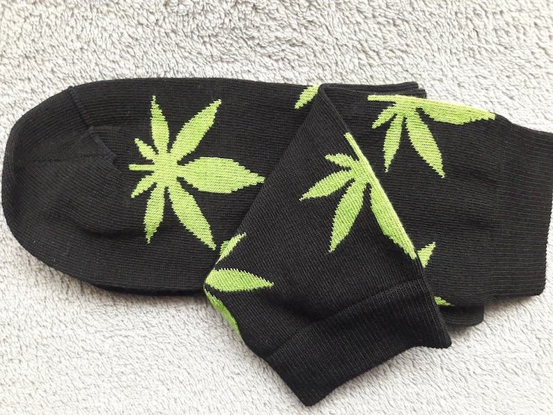 May include: A pair of black socks with a green marijuana leaf pattern.