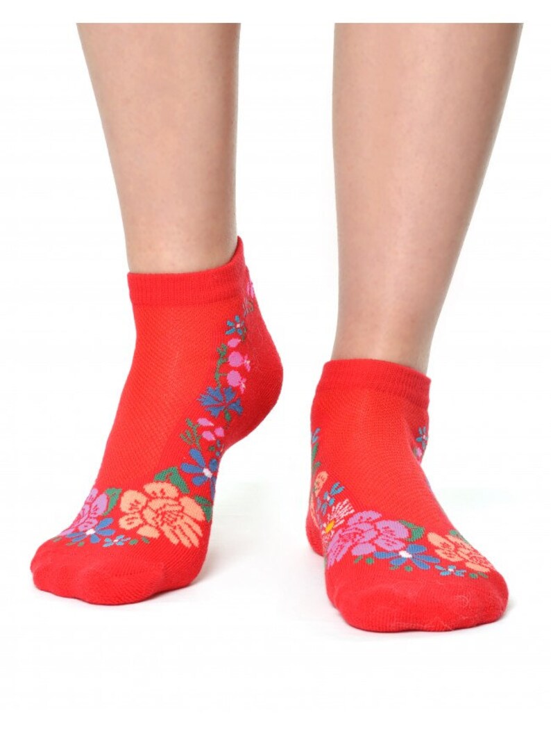 May include: Red ankle socks with a floral design. The flowers are pink, blue, and green.