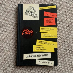 May include: A black book with a yellow and red title that reads "Memoirs of a Hound". The book cover also features a cartoon dog in a doghouse, the text "E. Walter", and the words "Memoirs of a Hound" in several languages.