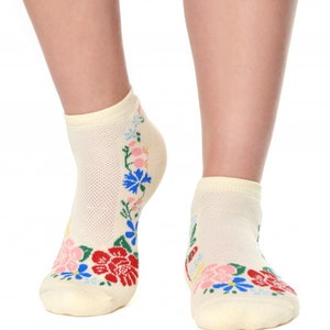 May include: A pair of cream-colored ankle socks with a floral design. The flowers are red, blue, pink, and yellow.