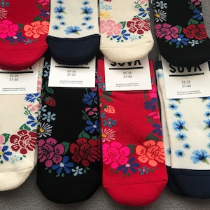 May include: Five pairs of colorful socks with floral patterns. The socks are white, red, black, and blue with different floral designs. The socks are labeled "SUVA" and have the size "23-25 37-40" printed on the tags.