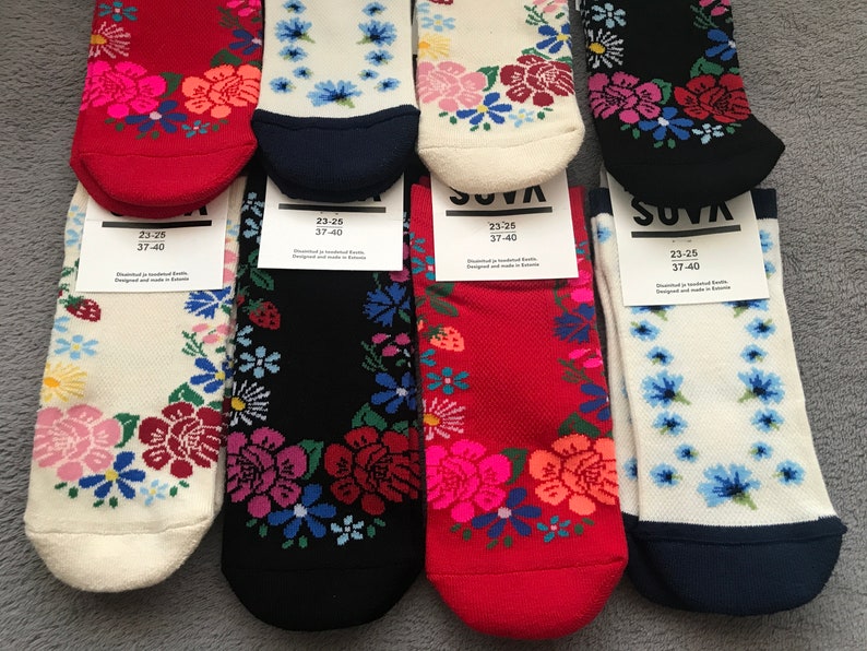 May include: Five pairs of colorful socks with floral patterns. The socks are white, red, black, and blue with different floral designs. The socks are labeled "SUVA" and have the size "23-25 37-40" printed on the tags.