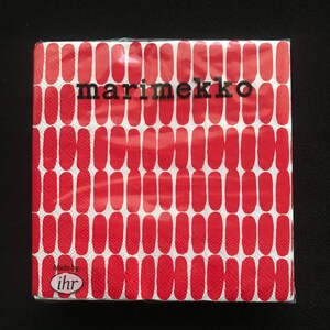May include: A package of Marimekko brand paper napkins. The napkins feature a repeating pattern of red, elongated ovals on a white background. The brand name is printed in black, and the package is sealed in clear plastic.