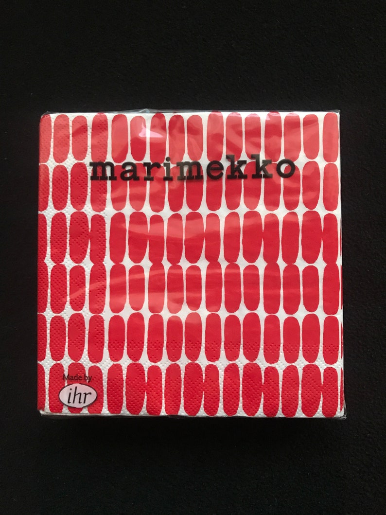May include: A package of Marimekko brand paper napkins. The napkins feature a repeating pattern of red, elongated ovals on a white background. The brand name is printed in black, and the package is sealed in clear plastic.