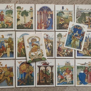 May include: A collection of medieval-style illustrated cards, featuring scenes with figures in period clothing, animals, and architectural elements. A small book with text and illustrations is also present.