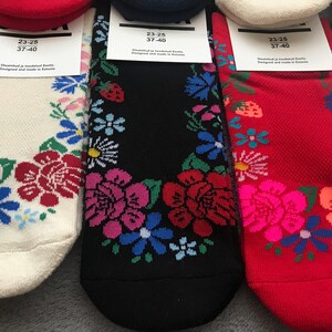 May include: Three pairs of socks with floral patterns. The socks are white, black, and red. The socks have a size tag that reads "23-25 37-40" and "Distributed ja tootundud Eesti. Designed and made in Estonia."