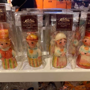 May include: Four individually packaged marzipan figurines in the shape of people wearing traditional clothing. The figurines are made by Kalev, a company that has been making marzipan since 1806. The packaging is clear plastic and the figurines are all different colors.