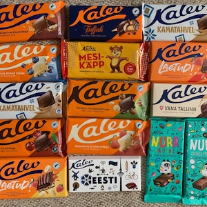 May include: A collection of 14 different chocolate bars from the Kalev brand. The bars are arranged in three rows, with four bars in each row. The bars are all wrapped in colorful foil and feature various designs and flavors. Some of the flavors include: Tiramisu, Mesi-Kapp, Kamatahvel, Laetud, and Vana Tallinn. The bars are all made in Estonia.