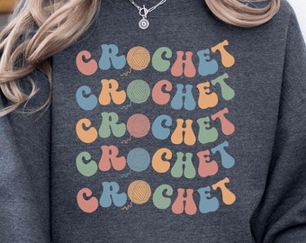 Puede incluir: Una sudadera gris oscuro con la palabra "CROCHET" repetida en una fuente retro colorida.
