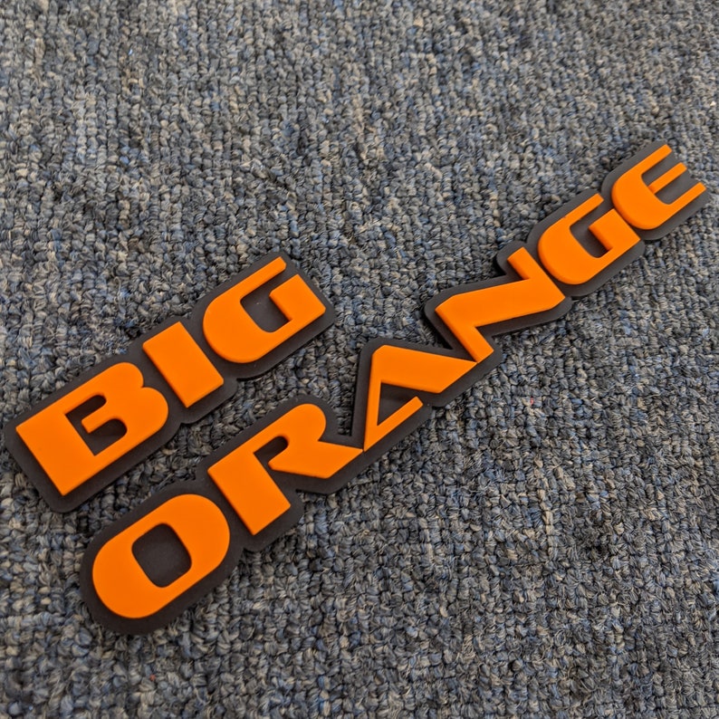 May include: A black and orange 3D emblem with the words "BIG ORANGE" in raised lettering.