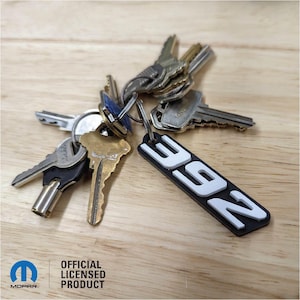 May include: A black and white keychain with the number "392" printed in white. The keychain is attached to a set of keys.