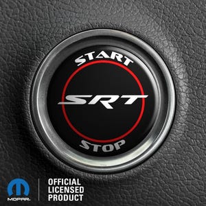 May include: A black and silver car steering wheel button with a red ring around the words "START" and "STOP" and the letters "SRT" in white.