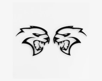 May include: A pair of black, stylized, facing, snarling, wolf-like heads. The heads are mirror images of each other.