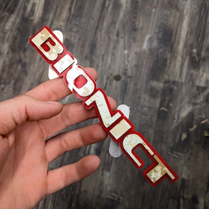 May include: A red and white camouflage sticker with the word "BioZic" printed on it.