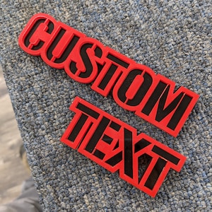 May include: Two red plastic signs with black lettering. The top sign says "CUSTOM" and the bottom sign says "TEXT".