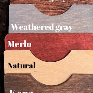 May include: A wood stain color chart with eight different wood stain colors. The colors are: White, Light Green, Red Mahogany, Weathered Gray, Merlot, Natural, Kona, and Aged Wheat.