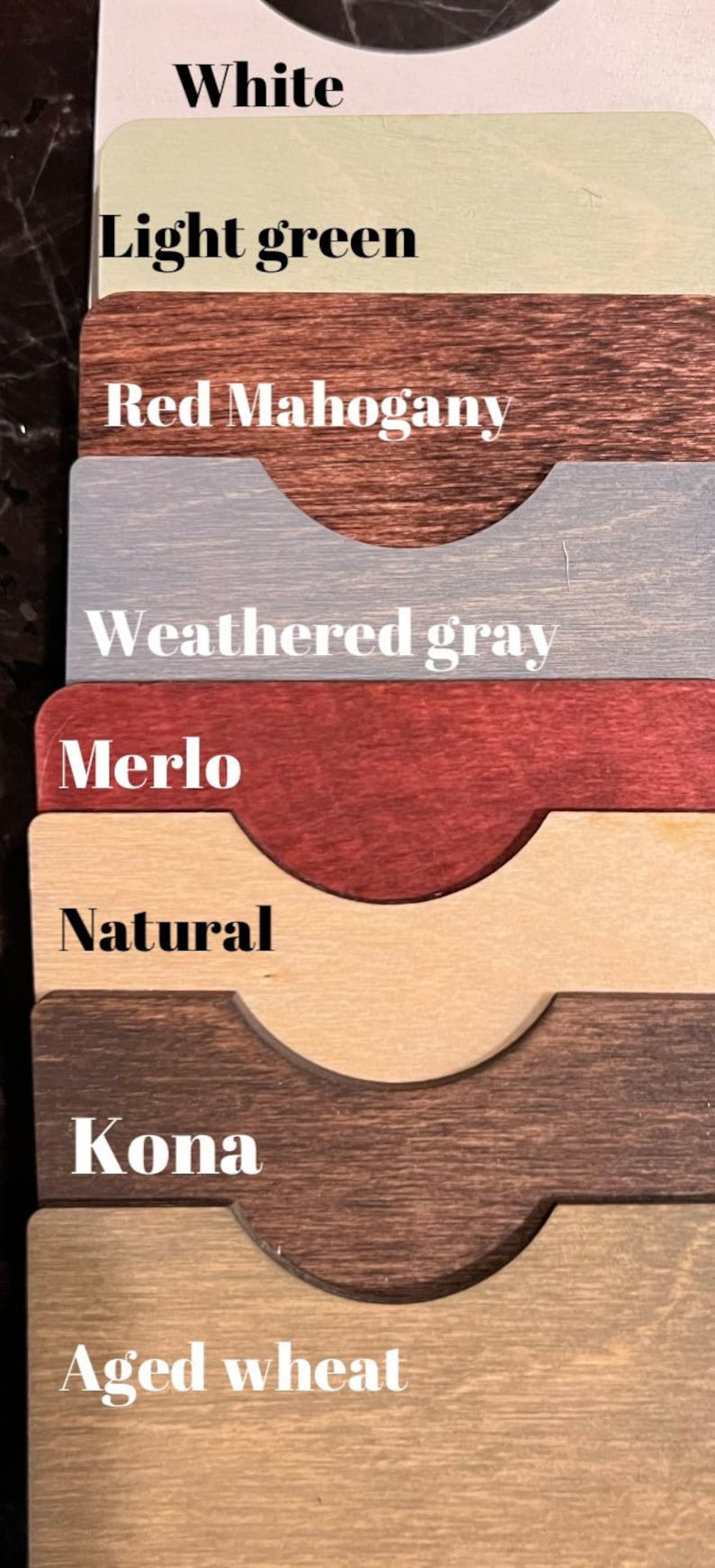 May include: A wood stain color chart with eight different wood stain colors. The colors are: White, Light Green, Red Mahogany, Weathered Gray, Merlot, Natural, Kona, and Aged Wheat.