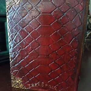 May include: A red leather-bound book with a gold embossed design and the text "TERROR POLL" on the bottom edge.