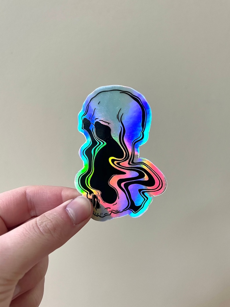 May include: A holographic sticker of a skull with a black and rainbow swirl design.