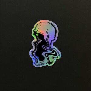 May include: A holographic sticker of a skull with a black and white liquid design inside. The skull is outlined in black and the liquid design is swirling and abstract.