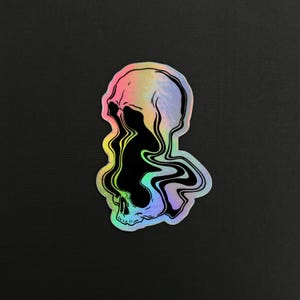 May include: A holographic sticker of a skull with a black, swirling, liquid-like design inside. The skull is outlined in black and has a rainbow iridescent background.