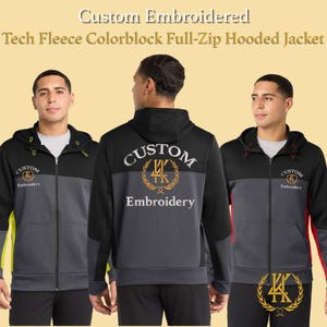 May include: A black, gray, and red colorblock full-zip hooded jacket with the text "Custom Embroidered" and "Embroidery". The jacket has a hood and a zipper closure. The design includes a logo on the front and back.