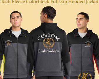 May include: A black, gray, and red colorblock full-zip hooded jacket with the text "Custom Embroidered" and "Embroidery". The jacket has a hood and a zipper closure. The design includes a logo on the front and back.