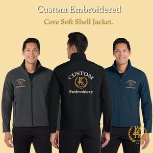Peut inclure: Trois hommes présentent des vestes Core Soft Shell personnalisées brodées. Les vestes sont présentées en gris anthracite, noir et bleu marine. Chaque veste a une fermeture éclair et le logo "Custom Embroidery" sur la poitrine et le dos.