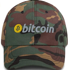 May include: A camouflage baseball cap with a yellow Bitcoin logo and the word "bitcoin" embroidered in white.