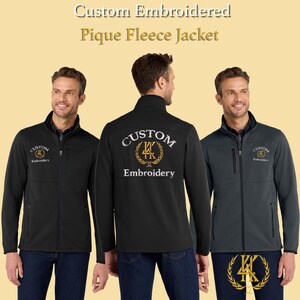 May include: Custom embroidered pique fleece jackets in black and charcoal gray. The jackets feature a zip-up front, side pockets, and custom embroidery on the chest and back. The text "Custom Embroidery" is displayed on the back.