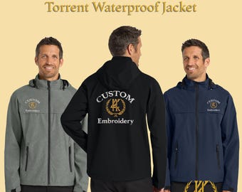 Può includere: Giacche impermeabili Torrent ricamate su misura in grigio, nero e blu navy. Ogni giacca presenta un cappuccio, una chiusura con cerniera e il logo "Custom Embroidery". Le giacche sono esposte su uno sfondo giallo chiaro.