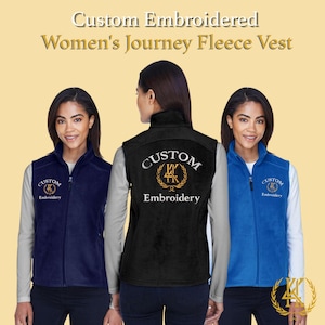 Può includere: Tre gilet in pile blu navy, nero e blu. Ogni gilet ha una chiusura con cerniera e la scritta "Custom Embroidery". I gilet sono indossati sopra una camicia a maniche lunghe. Il testo "Custom Embroidered Women's Journey Fleece Vest" è in alto.