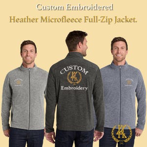 May include: Three men modeling heather microfleece full-zip jackets in gray and charcoal. The jackets have a stand-up collar and a full-length zipper. The text "Custom Embroidered" is displayed at the top of the image. The back of the charcoal jacket has the text "Custom Embroidery".