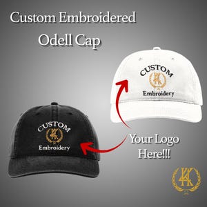May include: A black and a white Odell cap with custom embroidery. The caps have a curved brim and a six-panel design. The text on the caps reads "Custom Embroidery" with a gold emblem. The image also includes the text "Your Logo Here!!!".
