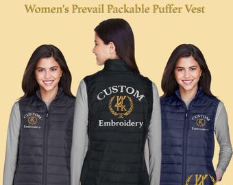 Puede incluir: Chalecos acolchados personalizados bordados en negro y azul marino. Los chalecos presentan un logotipo personalizado y las palabras "Custom Embroidery" bordadas en la parte delantera y trasera. Los chalecos se muestran en un modelo.
