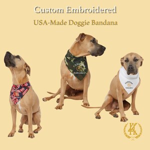 May include: Three dogs wearing custom embroidered doggie bandanas. One dog wears a red, white, and blue bandana with a stars and stripes design. Another dog wears a camouflage bandana. The third dog wears a white bandana.