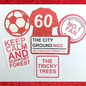 May include: Red and white glitter stickers with a football, a jersey with the number 60, a sign that says "Keep Calm and Support Forest", a sign that says "The City Ground NG2 Nottingham Forest F.C.", a sign that says "The Tricky Trees", and a round sticker that says "Nottingham No. 1 Fan".