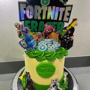 May include: A yellow and green birthday cake decorated with Fortnite characters and the words "Happy Birthday".
