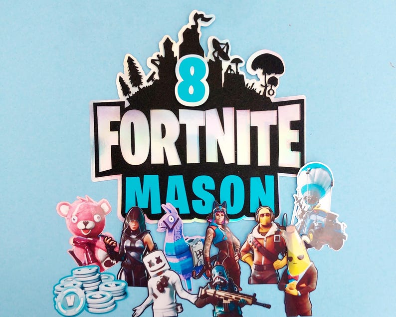 May include: A Fortnite themed cake topper with the words "Fortnite Mason 8" in blue and black lettering. The topper features various Fortnite characters, including a llama, a pink bear, and a masked figure.
