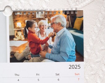 Op de afbeelding: Een kalender met een foto van drie mensen, een jong meisje, een vrouw en een man, die lachen en met elkaar omgaan. De kalender is voor het jaar 2025 en toont de maanden januari, februari, maart, april, mei, juni, juli, augustus, september, oktober, november en december.