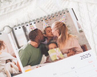 May include: A family of four wearing party hats, smiling and kissing. The image is part of a calendar with the year 2025 printed on it.