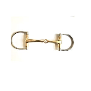 May include: A gold-colored horse bit with a stainless steel mouthpiece and two D-rings. The bit is designed for use with a horse's bridle.