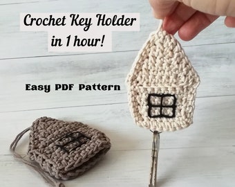 May include: Crocheted key holder in the shape of a house, with a black window detail. The key holder is beige and has a matching crocheted pouch. The text on the image says "Crochet Key Holder in 1 hour! Easy PDF Pattern."
