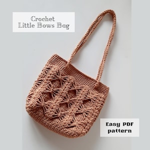 Pode incluir: Uma sacola tote de crochê cor de pêssego com um padrão de laço detalhado. A sacola tem duas alças e o texto "Crochet Little Bows Bag" e "Easy PDF pattern" são visíveis.