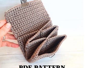 May include: A crocheted wallet in a neutral brown color, featuring multiple pockets and a metal clasp closure. The wallet is open, displaying the interior compartments. The text "PDF PATTERN" is printed at the bottom.