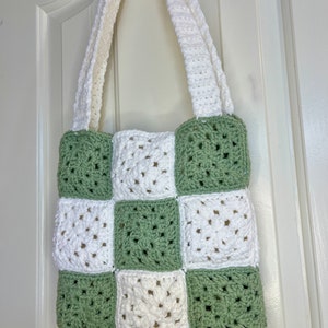 May include: A crocheted tote bag with white and green squares. The bag has two long straps.