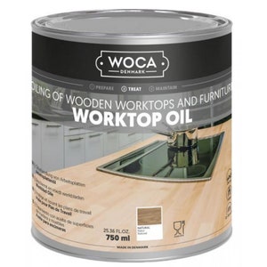 Könnte beinhalten: Eine Dose WOCA Worktop Oil, eine Holzversiegelung für Arbeitsplatten und Möbel. Die Dose ist silberfarben mit schwarzem Text und einem Bild einer Küchenarbeitsplatte. Der Text auf der Dose lautet "WOCA Dänemark" und "Oiling of Wooden Worktops and Furniture Worktop Oil". Die Dose enthält 750 ml (25.36 fl oz).