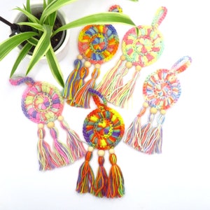 Könnte beinhalten: Fünf bunte gehäkelte Traumfänger mit Holzperlen und Quasten. Jeder Traumfänger hat ein kreisförmiges Design mit einer Vielzahl von Farben, darunter Pink, Gelb, Orange, Blau und Grün.