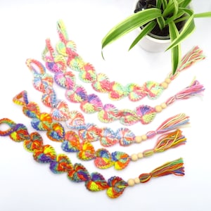 Peut inclure: Cinq porte-clés en crochet en forme de cœur colorés avec des perles en bois et des glands. Les porte-clés sont faits de différentes couleurs, notamment le rose, le violet, le bleu, le jaune et l'orange.